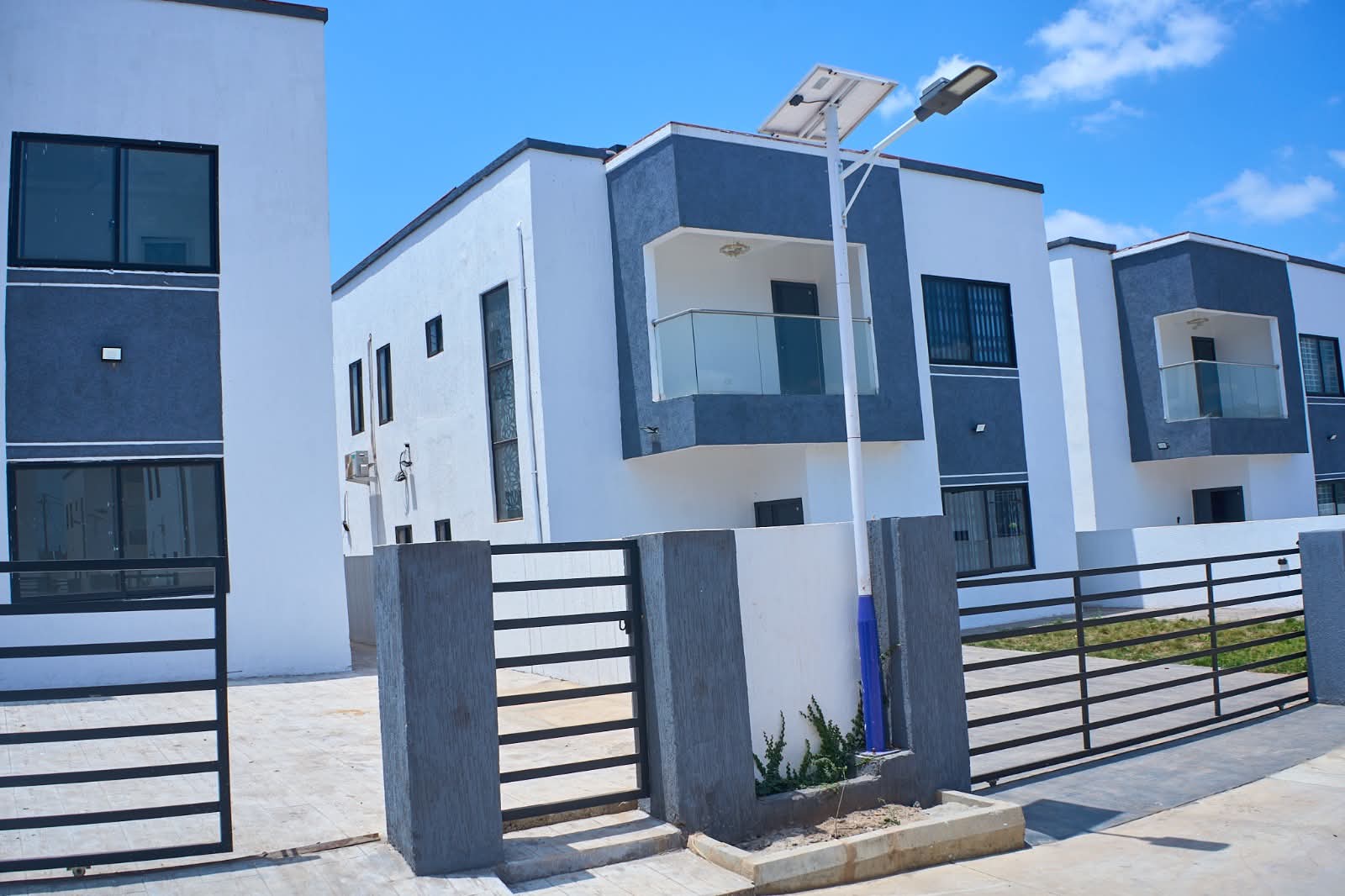 A finished home with a glass balcony behind its front gate